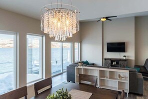 A modern living room with a large chandelier, a flat-screen TV, and a view of the water. - Lakefront 3BR with private dock & amazing views (Chelan)