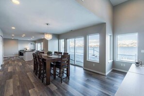 A spacious kitchen with a dining area, large windows, and a view of a snowy landscape. - Lakefront 3BR with private dock & amazing views (Chelan)