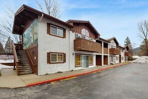 A multi-story building with a covered entrance and a staircase leading to the ground floor. - Downtown Studio Mountainview 1st-Floor - Patio (Leavenworth)