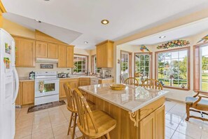A kitchen with wooden cabinets, a central island, and a view of the outdoors through large windows.