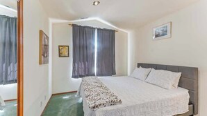 A bedroom with a bed, curtains, a framed picture, and a mirror. - Spanish-style 6BR Mountainview - Deck - W&D (East Wenatchee)