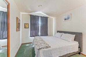 A bedroom with a bed, curtains, a framed picture, and a mirror. - Spanish-style 6BR Mountainview - Deck - W&D (East Wenatchee)