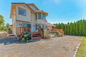 A two-story house with a front porch, a covered patio, and a well-maintained lawn. - Spanish-style 6BR Mountainview - Deck - W&D (East Wenatchee)