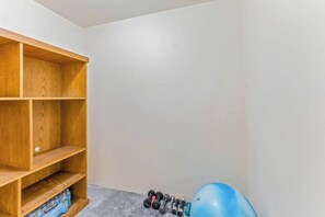 A corner of a room with a wooden shelf unit and a set of dumbbells on the floor.