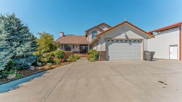 A residential house with a garage, a driveway, and a well-maintained garden. - Spanish-style 6BR Mountainview - Deck - W&D (East Wenatchee)