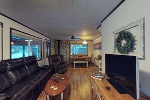 Ein Wohnzimmer mit einer Ledersofa, einem Couchtisch, einem Fernseher und einer Steinwand.