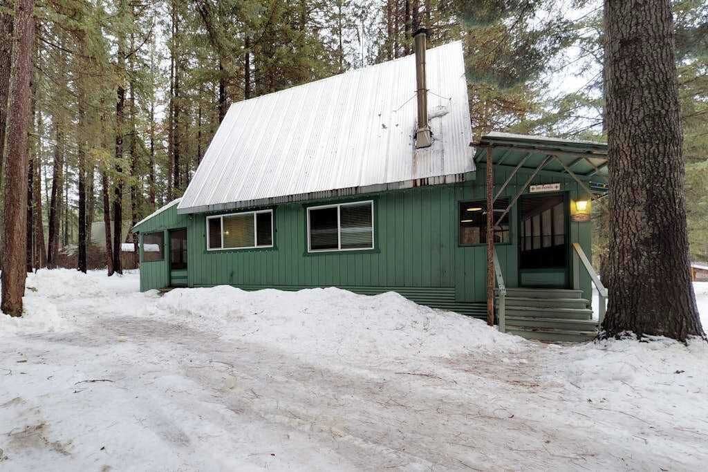 Un bâtiment écologique doté d’un toit en métal, entouré d’arbres et recouvert de neige.