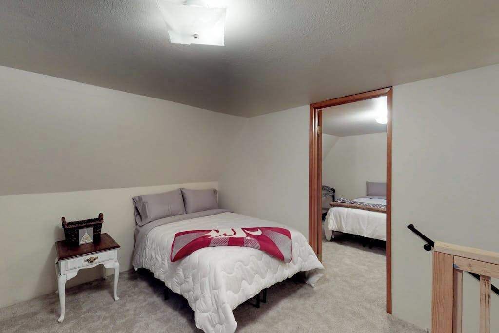 A bedroom with a bed, a nightstand, a mirror, and a door.