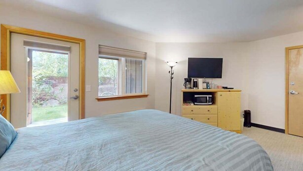 A bedroom with a bed, a television, a desk with a computer, and a window. - Downtown Studio 1st-Floor - Icicle Village Resort (Leavenworth)