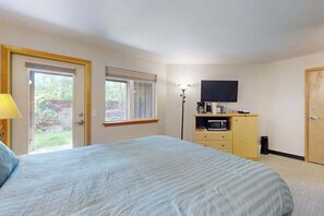 A bedroom with a bed, a television, a desk with a computer, and a window. - Downtown Studio 1st-Floor - Icicle Village Resort (Leavenworth)