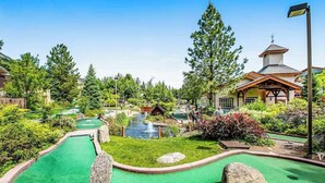 A miniature golf course with a putting green, a water hazard, and a small building with a tower. - Downtown Studio 1st-Floor - Icicle Village Resort (Leavenworth)