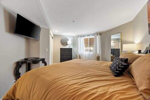 Een slaapkamer met een bed, een televisie aan de muur, een dressoir en een spiegel.