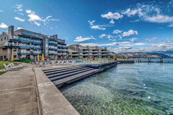 Een hotel met een zwembad, terras en uitzicht op bergen.