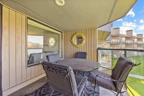 A balcony with a round table and chairs, a view of the landscape, and a circular mirror on the wall.
