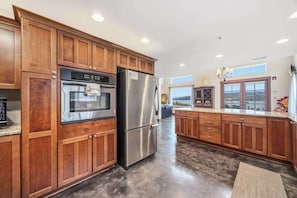 A kitchen with wooden cabinets, stainless steel appliances, and a view through the window. - 2BR home with great views & located on winery (Chelan)