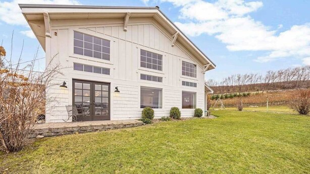 Ein zweistöckiges Haus mit Veranda, Garage und gepflegtem Rasen.