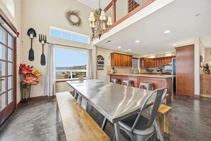 A spacious kitchen with a long dining table, wooden cabinets, and a view of the outdoors. - 2BR home with great views & located on winery (Chelan)