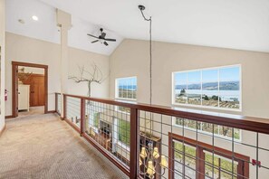 Ein großzügiger Innenraum mit hoher Decke, einem Deckenventilator und Blick ins Freie durch große Fenster.