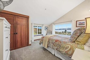Ein Schlafzimmer mit einem großen Bett, einem Kleiderschrank und zwei Fenstern mit Blick.