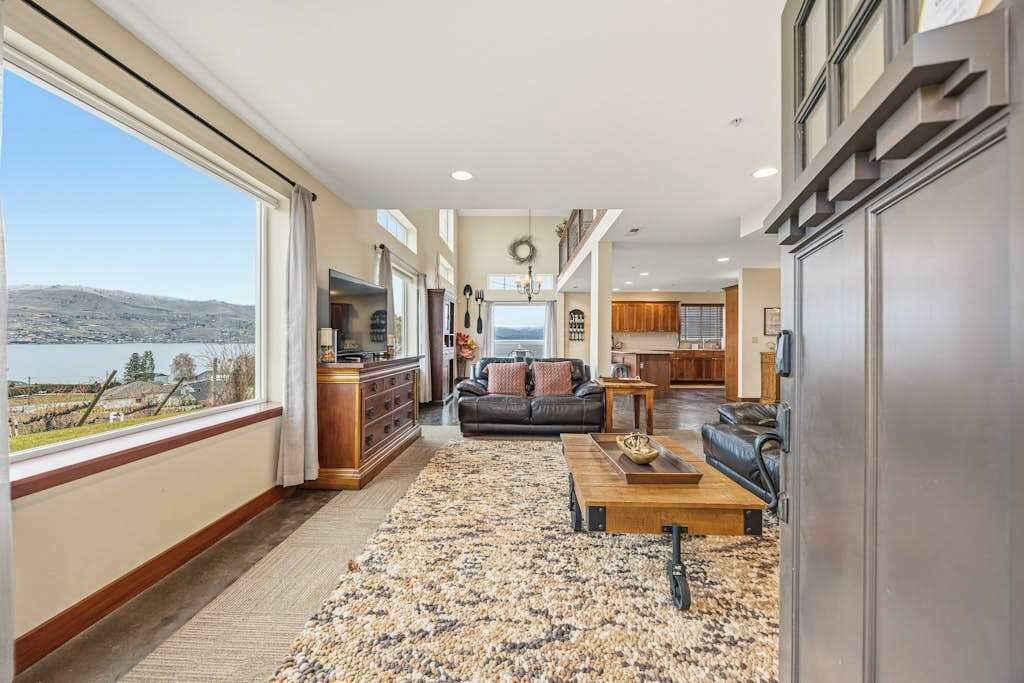 A spacious living area with a large window, a fireplace, and a view of a lake.