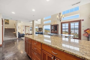 Eine geräumige Küche mit Granitarbeitsplatte, Holzschränken und Blick durch große Fenster.