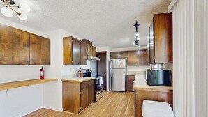 A kitchen with wooden cabinets, stainless steel appliances, and a wooden countertop. - 3BR Home & Bunk Room with hot tub, mountain views (East Wenatchee)