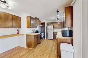 A kitchen with wooden cabinets, stainless steel appliances, and a wooden countertop. - 3BR Home & Bunk Room with hot tub, mountain views (East Wenatchee)