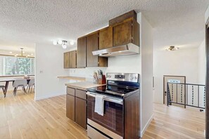 Una cocina moderna con armarios de madera, electrodomésticos de acero inoxidable y un comedor con mesa y sillas.