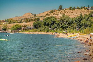 A coastal area with a beach, boats, and a hilly backdrop. - Updated 3BR Lakeview - Balcony - Washer/Dryer (Chelan)