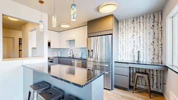 A modern kitchen with a central island, stainless steel appliances, and pendant lighting.