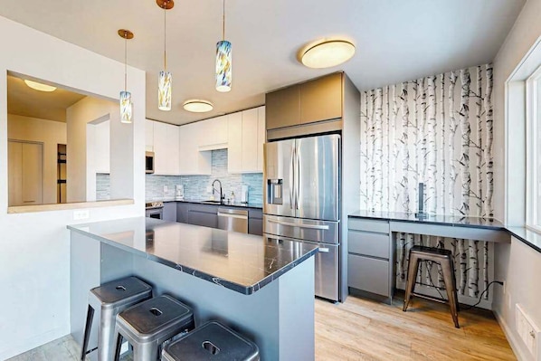 A modern kitchen with a central island, stainless steel appliances, and pendant lighting.