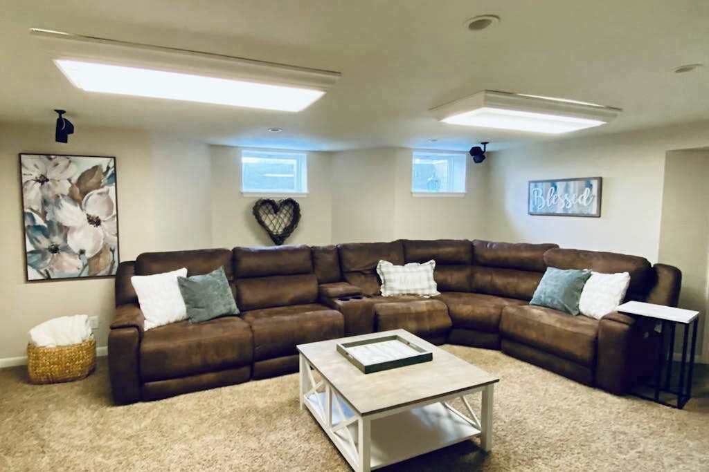 A living room with a brown leather sectional sofa, a light-colored coffee table, and a framed picture on the wall.