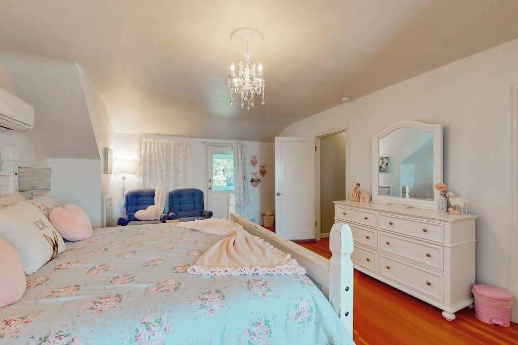 Un dormitorio con cama, cómoda y lámpara de araña.