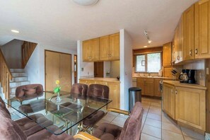Une cuisine moderne avec des meubles en bois, une table à manger en verre et une machine à café.