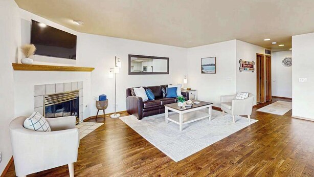 A modern living room with a fireplace, a sofa, a coffee table, and a TV mounted on the wall. - 2BR lakeside condo with shared pools and hot tub (Chelan)