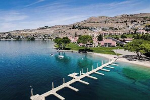 A coastal hotel with a marina, clear blue water, and a hilly backdrop. - 2BR lakeside condo with shared pools and hot tub (Chelan)