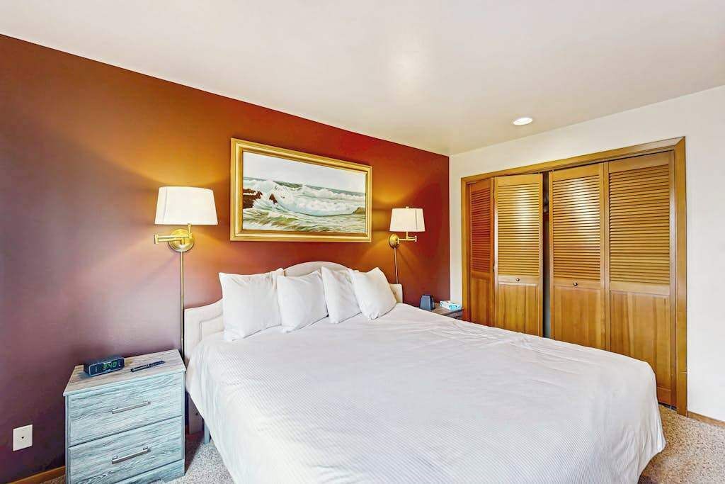 Habitación de hotel con cama, lámparas de noche, mesita de noche, un cuadro y un armario.