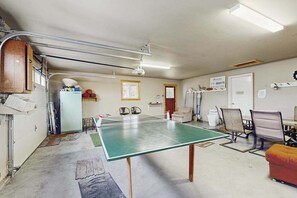 Ein Zimmer mit Tischtennisplatte, Stühlen, einer kleinen Küchenzeile und einer Tür mit einem Schild.