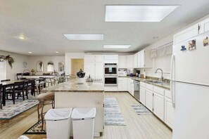 A modern kitchen with white cabinetry, a central island, and a dining area with chairs.