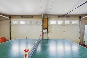 Eine Garage mit Tischtennisplatte, zwei Garagentoren und einem Holzschrank.