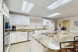 Une cuisine moderne avec des meubles blancs, un plan de travail en granit et des appareils électroménagers intégrés.