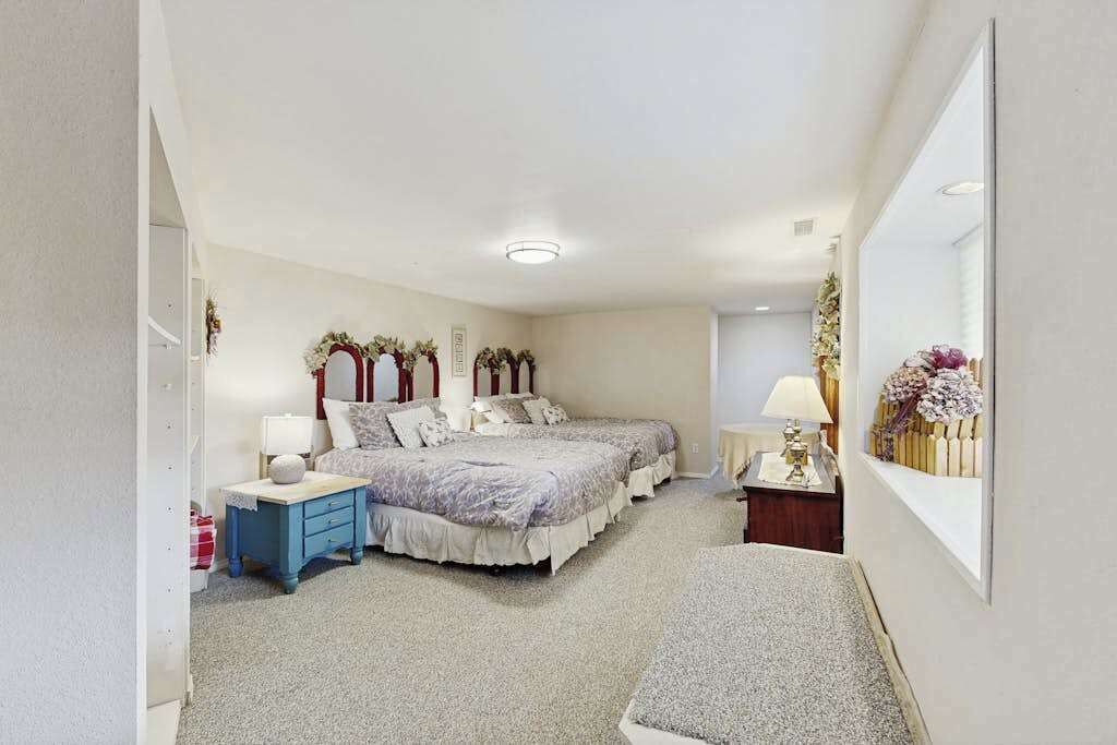 Ein Schlafzimmer mit zwei Betten, einem Nachttisch, einem Spiegel und einem an der Wand befestigten Regal mit Blumen.
