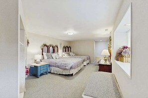 Ein Schlafzimmer mit zwei Betten, einem Nachttisch, einem Spiegel und einem an der Wand befestigten Regal mit Blumen.