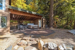 Eine Hütte mit überdachter Terrasse, Grill und Sitzgelegenheit.