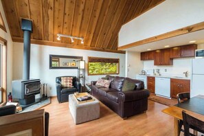 Ein Wohnzimmer mit Kamin, Ledersofa, Hocker und einem Essbereich mit Tisch und Stühlen.