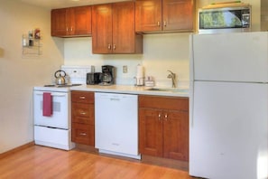 A kitchen with wooden cabinets, a white refrigerator, a microwave, a dishwasher, and a kettle. - Lake-view 3BR - private hot tub, dog-friendly (Leavenworth)