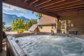 A hot tub area with a wooden structure, a view of mountains, and a building with a red roof. - Lake-view 3BR - private hot tub, dog-friendly (Leavenworth)