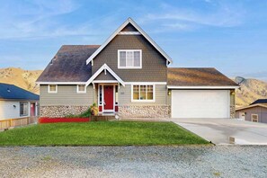 A residential house with a red door, a garage, and a well-maintained lawn. - Three BR home with great views & location (Orondo)