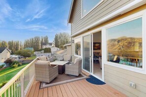 A balcony with outdoor furniture, a sliding glass door, and a view of a pool and hills. - Three BR home with great views & location (Orondo)