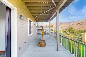 A covered balcony with a view of a hilly landscape.